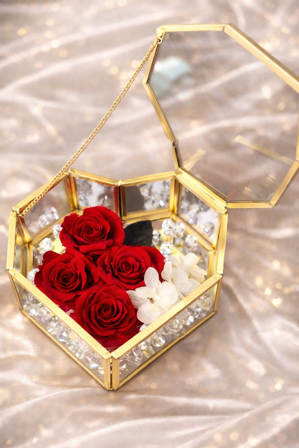 Hexagonal gold frame with red roses and white flowers on a reflective surface